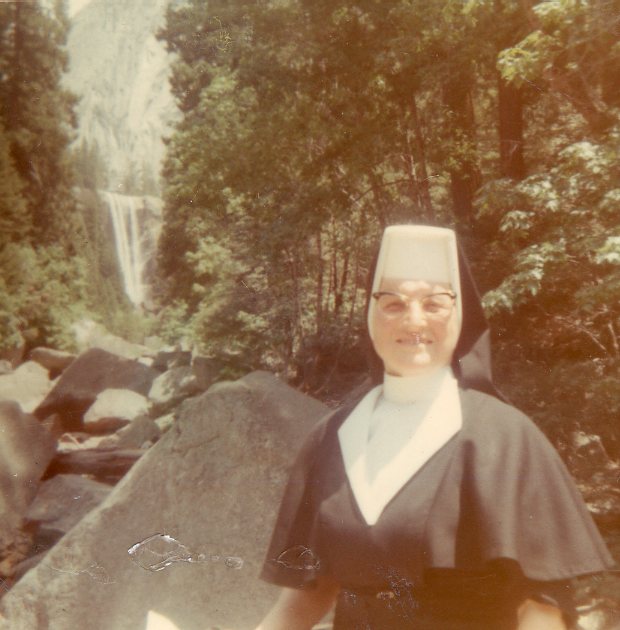 Sister Antonita Emge in habit standing in front of a waterfall.