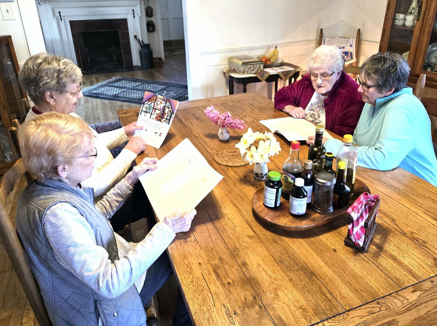 Four senior women sitting at a table with reading materials