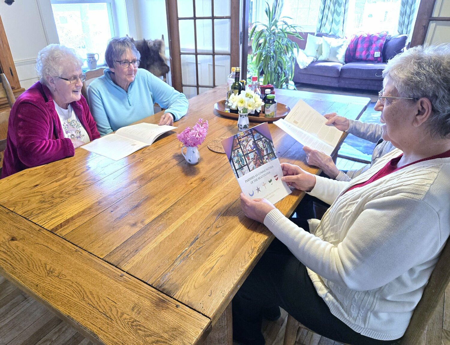 Senior women sitting at a table with reading material.