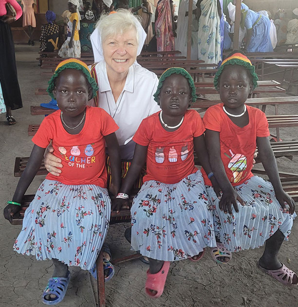 Sister Anna Marie Reha, SSND, sits with three girls while serving in South Sudan, Africa.