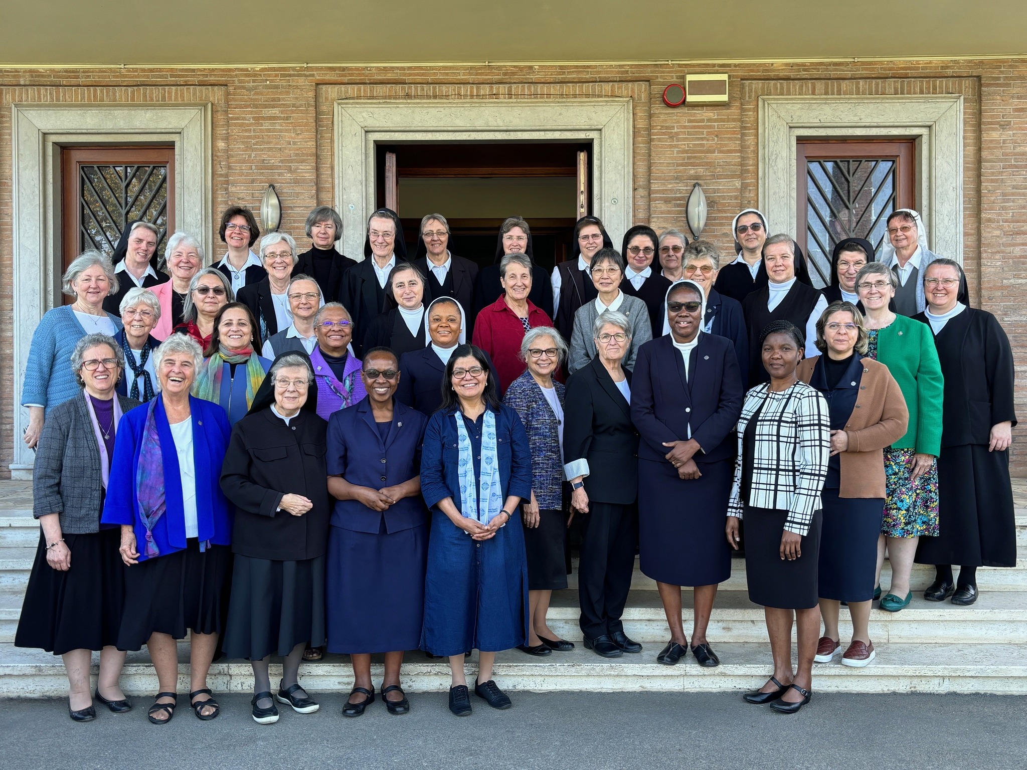 Several women gathered on the steps in front of a buildng.