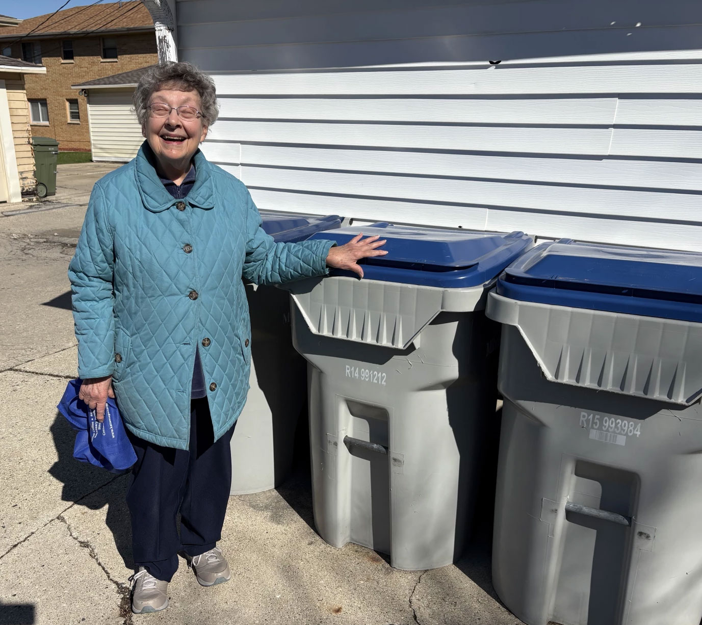 Sister Joanne Poehlman stands in front of recycling bins.