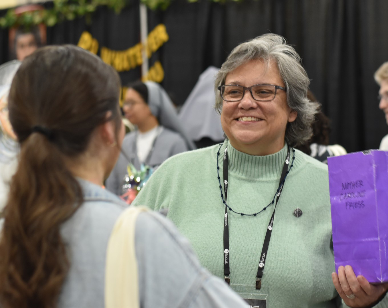 Sister Bridget Waldorf shares a quote from Mother Caroline Friess with a participant at the SEEK26 Conference in Fort Worth, Texas. 